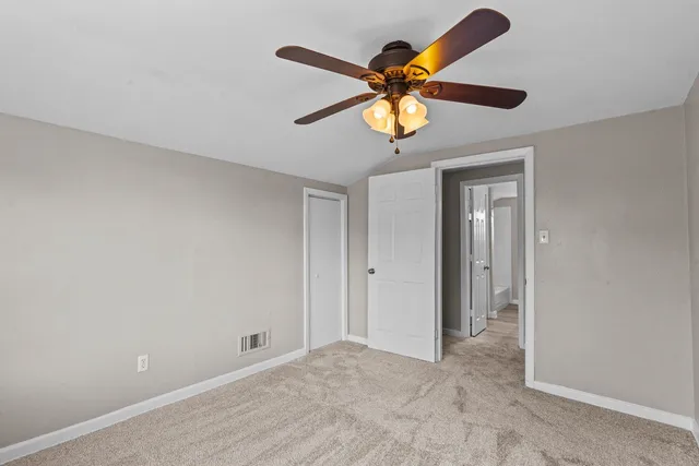 an empty room with a ceiling fan and a window