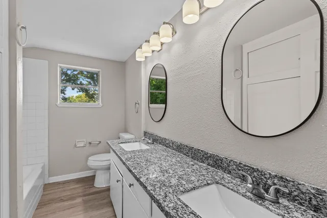 a bathroom with a granite countertop toilet sink and mirror