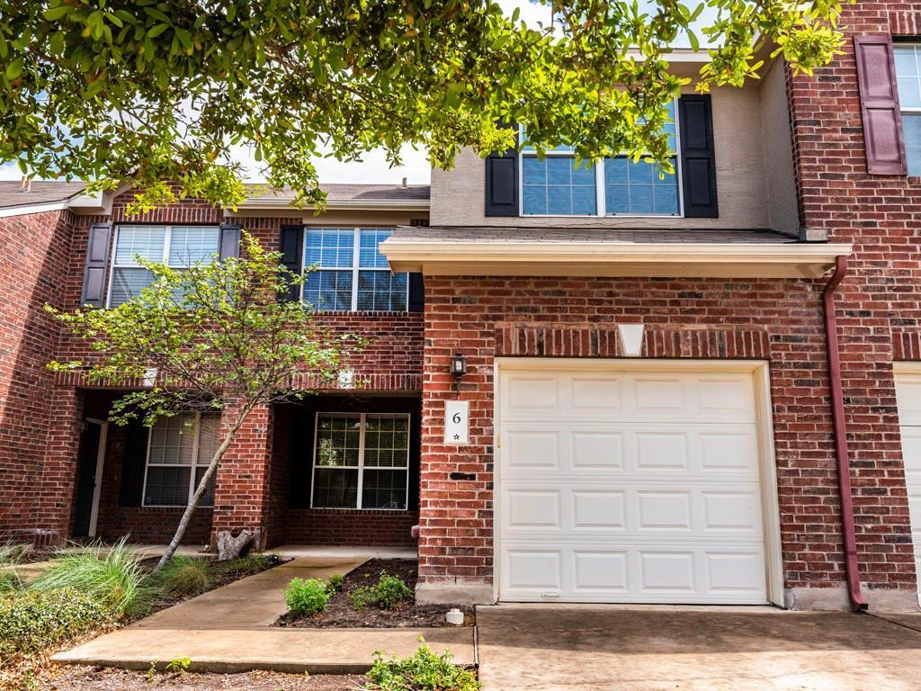 Traditional-style house featuring a garage, brick siding, and driveway