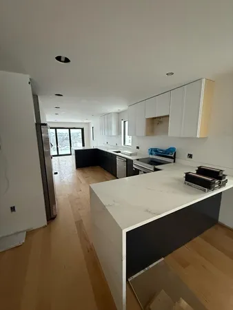 a kitchen with stainless steel appliances a sink a stove a refrigerator a white cabinet with grey walls