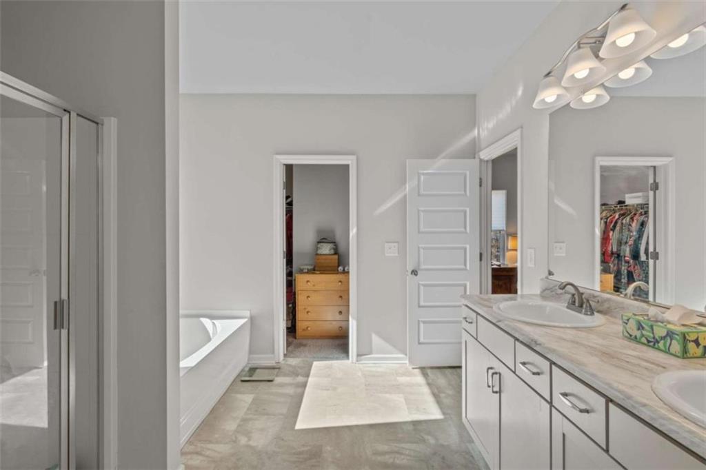 9068 Jim Purcell Drive Covington, GA 30014 - Photo 29 of 48 a spacious bathroom with a granite countertop sink a mirror and a shower