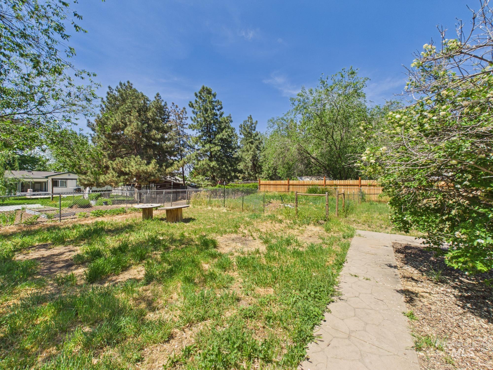 1527 North Plaza Road Emmett, ID 83617 - Photo 31 of 33 Expansive outdoor space featuring a patterned stone pathway, mature perimeter trees, and a wooden fence