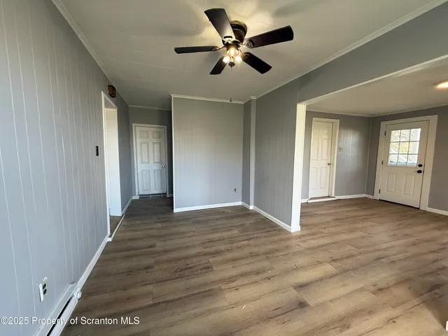 a view of an empty room with window and a chandelier fan