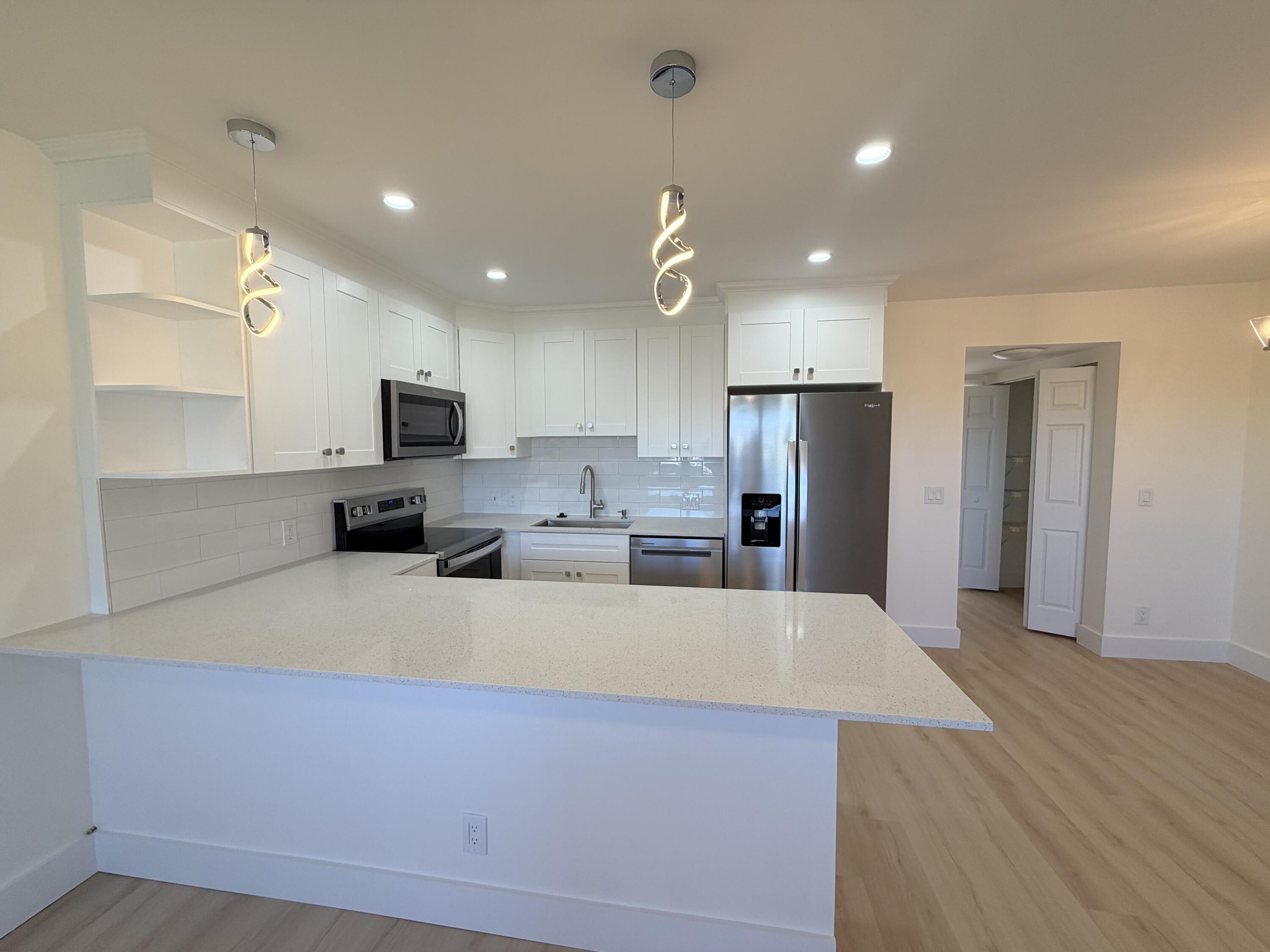 a large kitchen with kitchen island a large counter top stainless steel appliances and cabinets