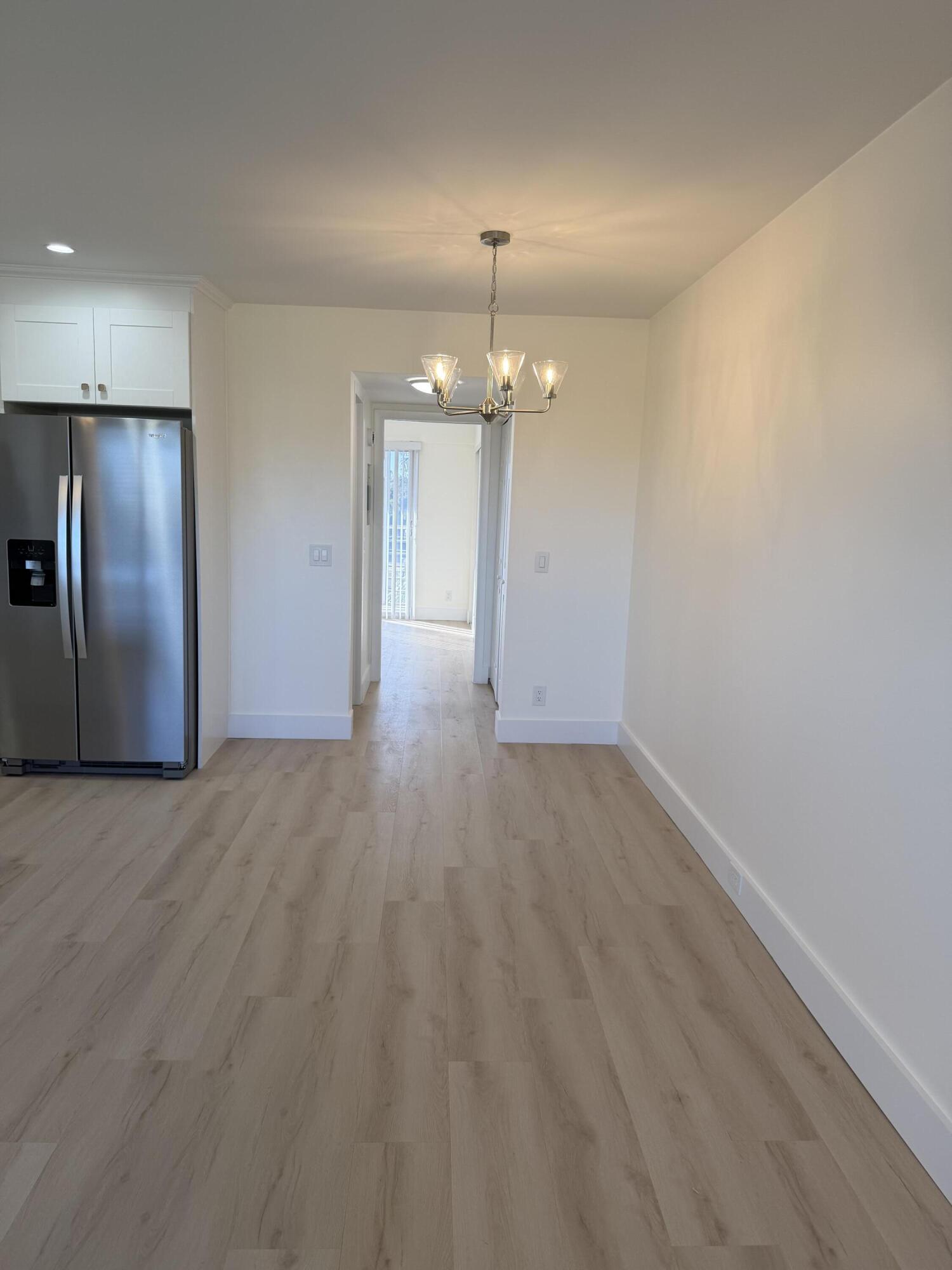 37 Suffolk Way Boca Raton, FL 33434 - Photo 37 of 40 an empty room with wooden floor chandelier and refrigerator