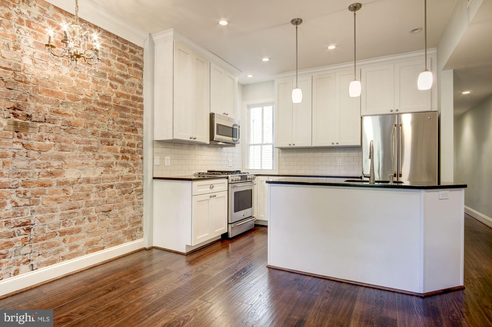 3040 R Street Northwest, Unit 1/2 Washington, DC 20007 - Photo 7 of 33 a kitchen with stainless steel appliances granite countertop a refrigerator a stove a sink and white cabinets with wooden floor