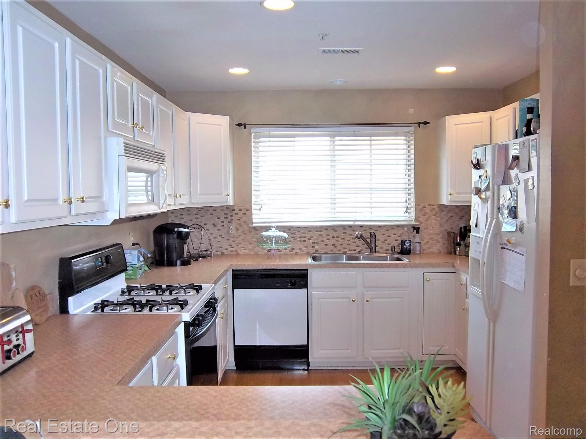 16802 Farmington Road Livonia, MI 48154 - Photo 7 of 23 KITCHEN WITH WHITE CABINETS AND WOOD FLOOR