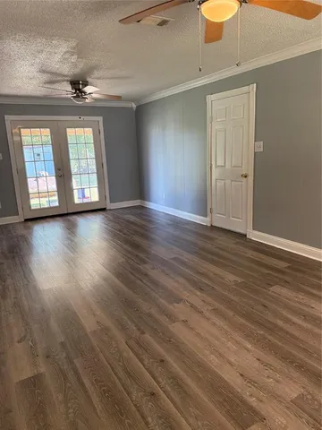 a view of an empty room with wooden floor and fan