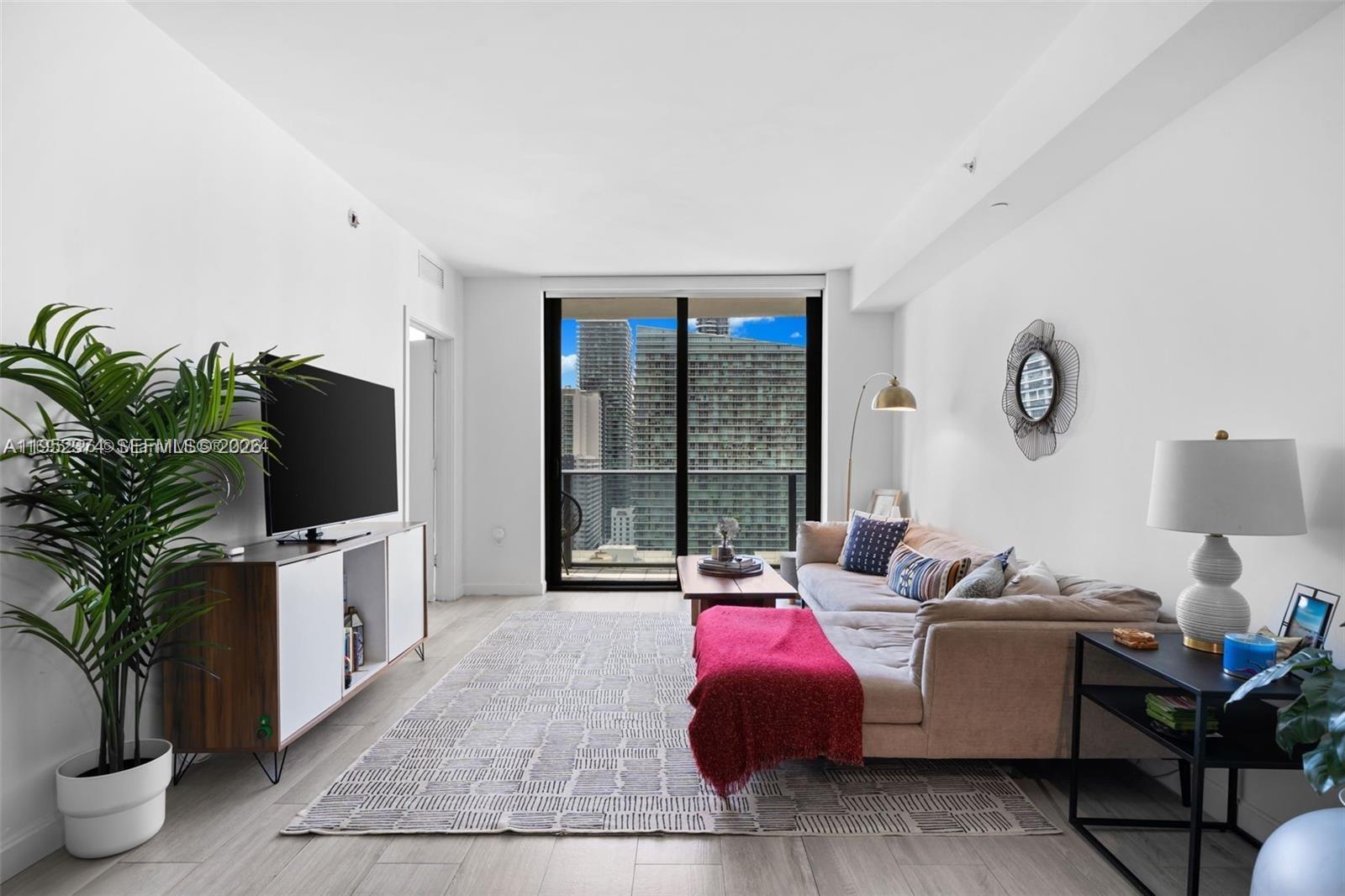 55 Southwest 9th Street, Unit 2305 Miami, FL 33130 - Photo 3 of 23 a living room with furniture and a flat screen tv