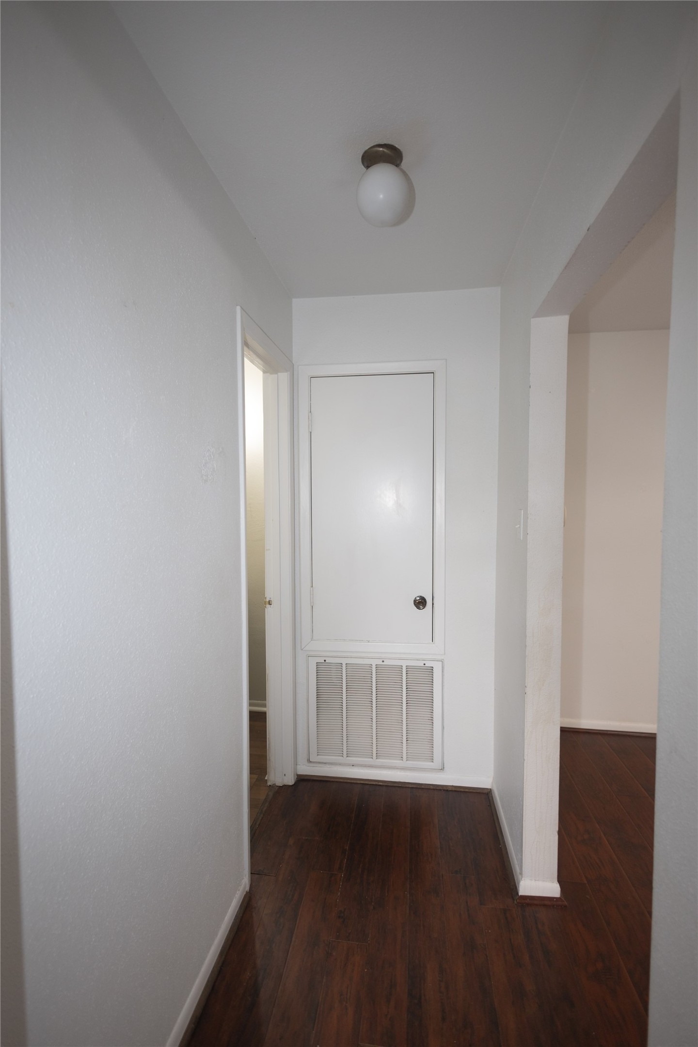 8100 Cambridge Street, Unit 89 Houston, TX 77054 - Photo 13 of 41 Hallway with dark wood flooring, fresh white walls, and modern lighting leading to the downstairs secondary bedroom and secondary bathroom.