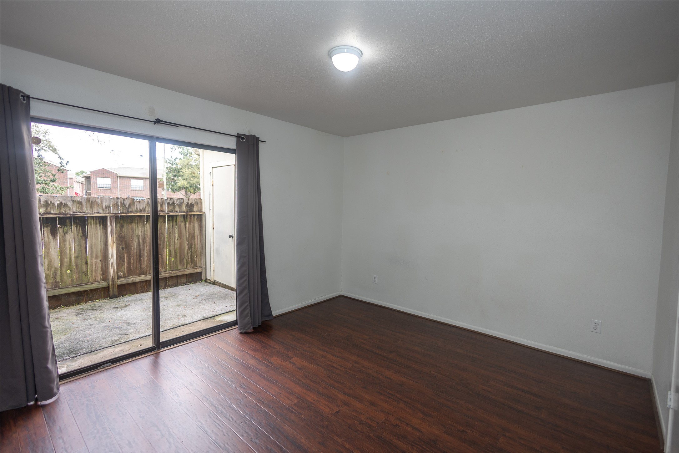 8100 Cambridge Street, Unit 89 Houston, TX 77054 - Photo 14 of 41 Downstairs secondary bedroom with dark wood flooring and sliding glass doors offering direct access to the private patio