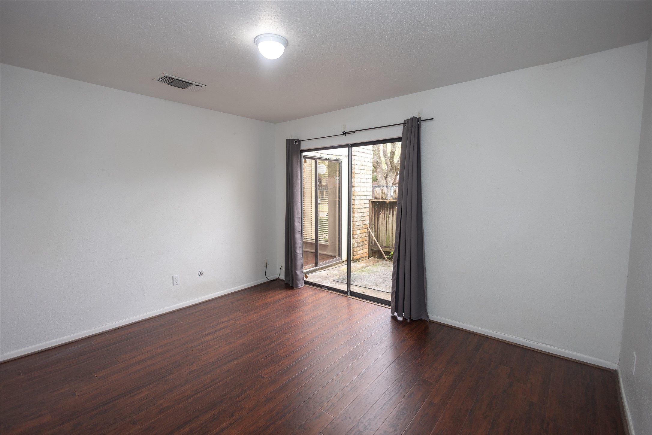8100 Cambridge Street, Unit 89 Houston, TX 77054 - Photo 15 of 41 Downstairs secondary bedroom with dark wood flooring and sliding glass doors offering direct access to the private patio