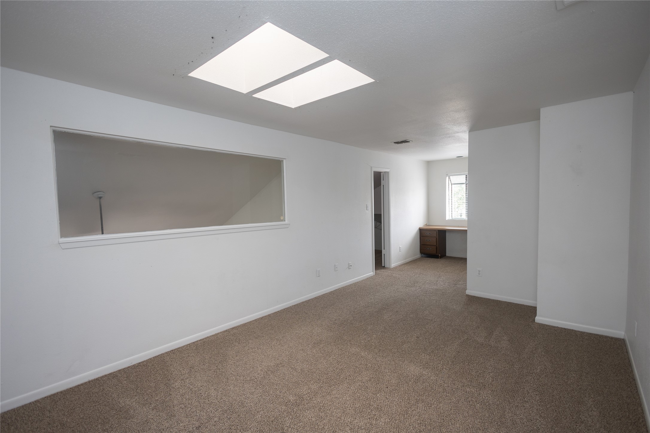 8100 Cambridge Street, Unit 89 Houston, TX 77054 - Photo 27 of 41 Upstairs primary bedroom with skylights, neutral carpet, and an open layout filled with natural light