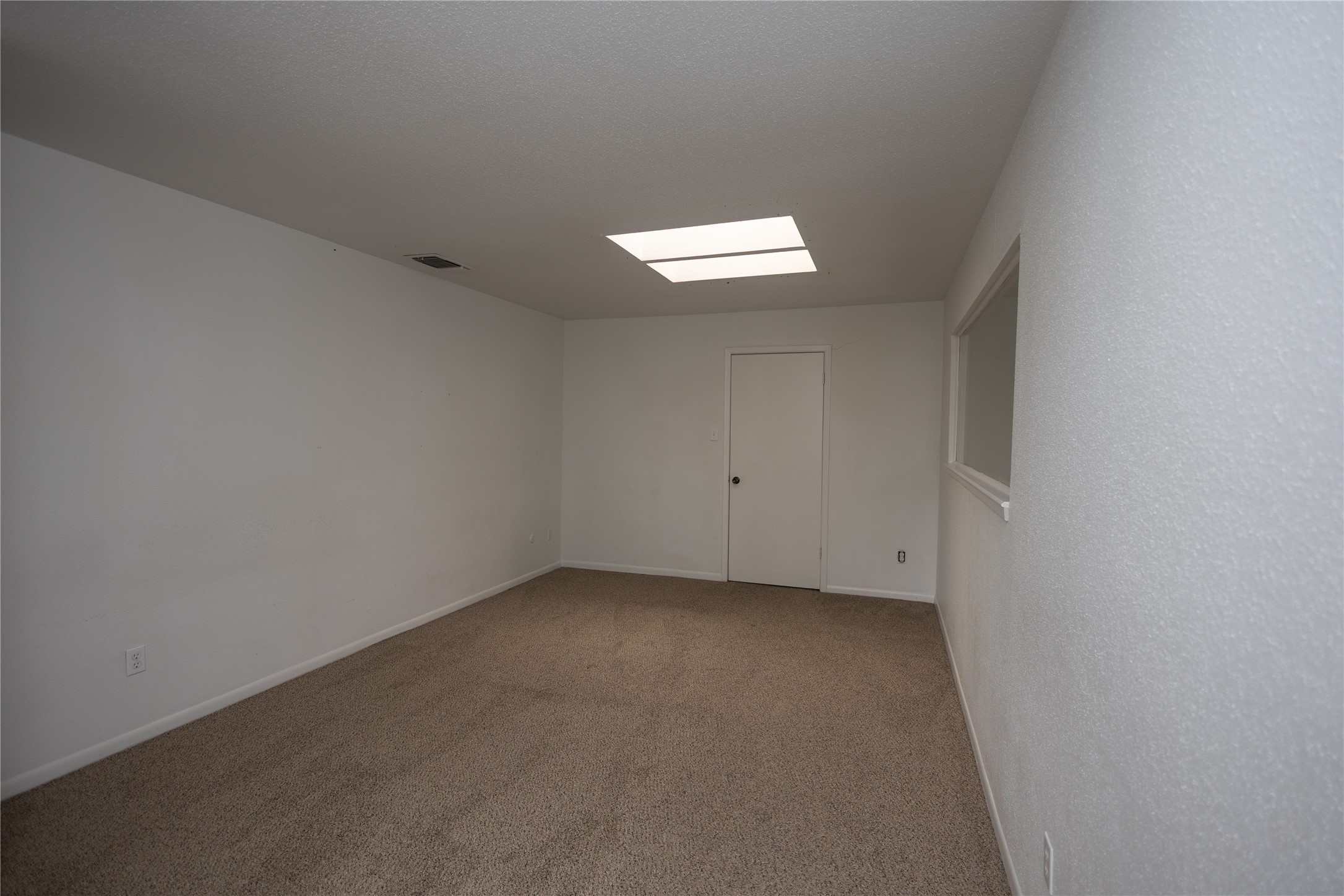 8100 Cambridge Street, Unit 89 Houston, TX 77054 - Photo 29 of 41 Upstairs primary bedroom with skylights, neutral carpet, and an open layout filled with natural light