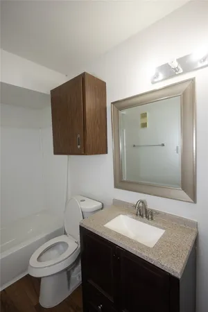 a bathroom with a granite countertop toilet sink and mirror