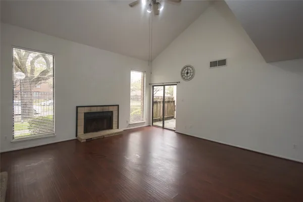 an empty room with wooden floor fireplace and windows