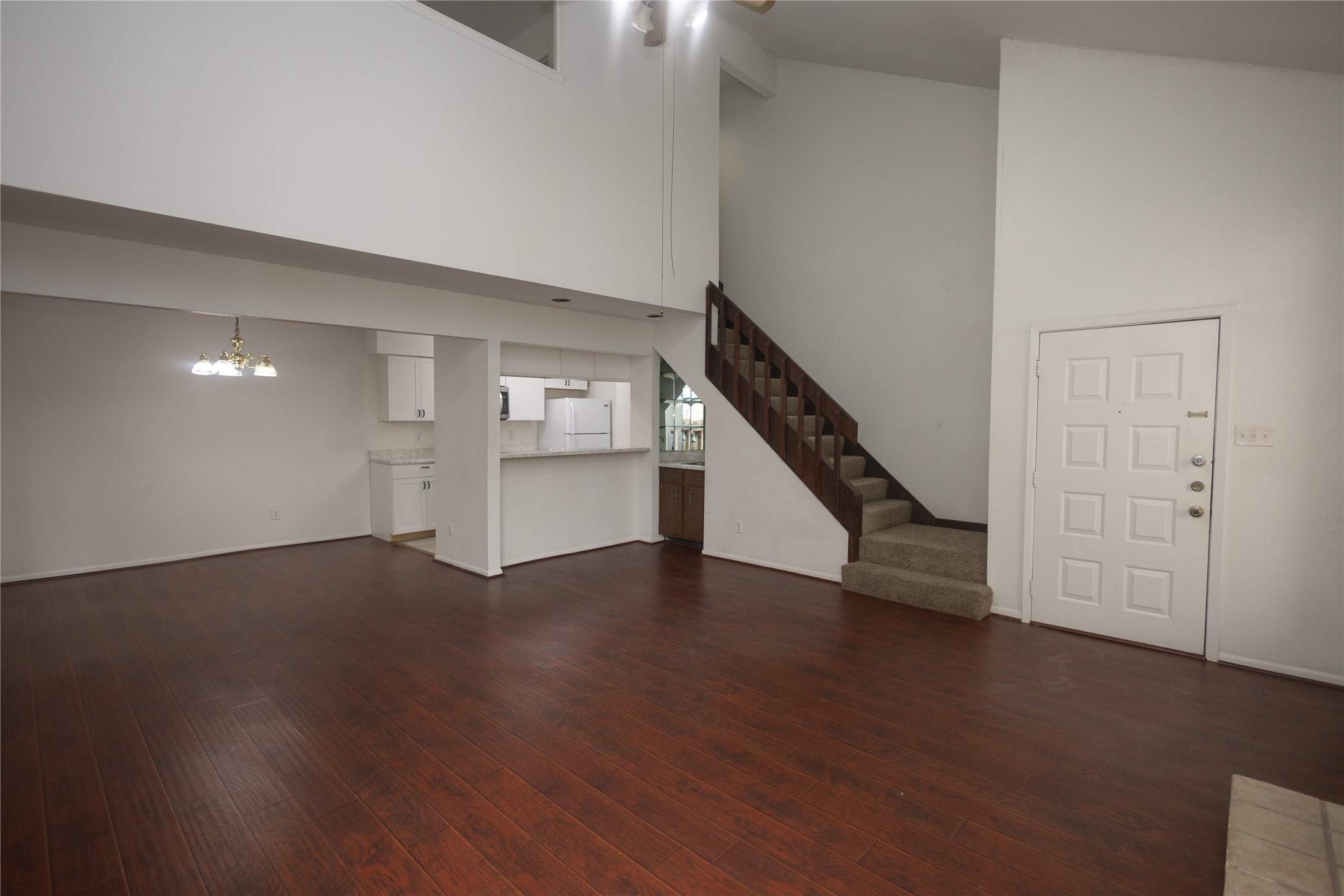8100 Cambridge Street, Unit 89 Houston, TX 77054 - Photo 6 of 41 Open living and dining area with dark wood floors, high ceilings, a breakfast bar, and a staircase leading to the upper level