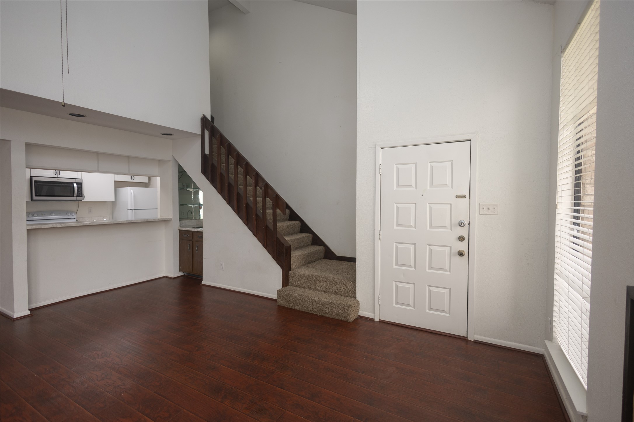8100 Cambridge Street, Unit 89 Houston, TX 77054 - Photo 7 of 41 Open living and dining area with dark wood floors, high ceilings, a breakfast bar, and a staircase leading to the upper level