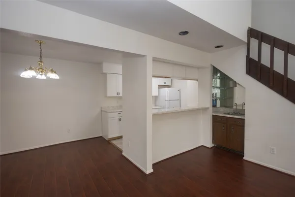a view of kitchen and empty room with wooden floor