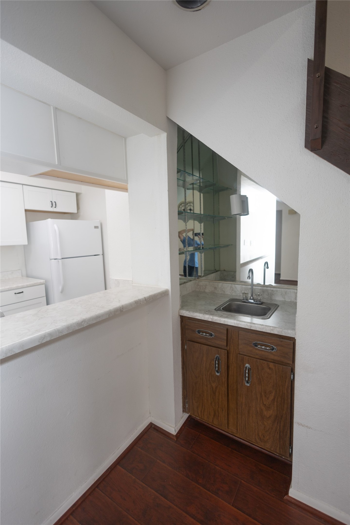 8100 Cambridge Street, Unit 89 Houston, TX 77054 - Photo 9 of 41 Compact kitchen with adjacent wet bar featuring a sink, mirrored shelving, and storage tucked efficiently under the staircase.