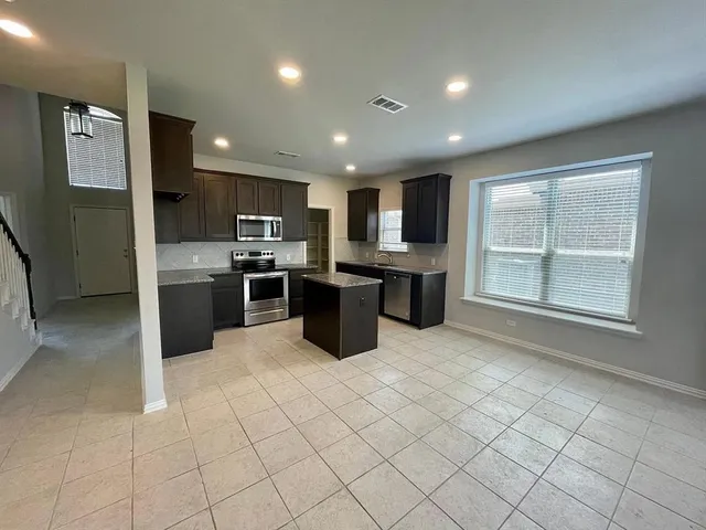a kitchen with stainless steel appliances granite countertop a refrigerator and a stove top oven