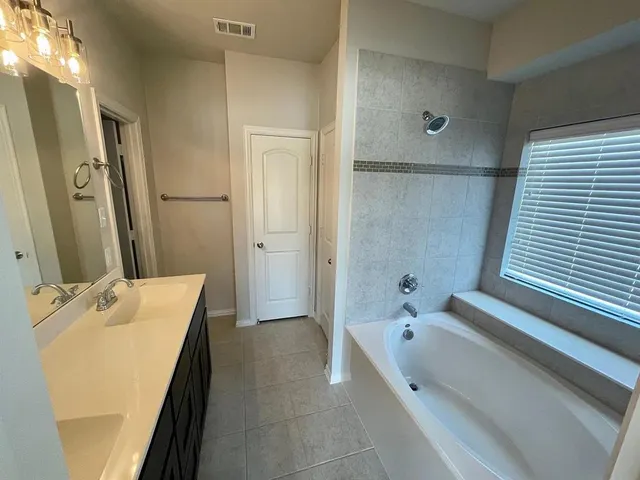 a spacious bathroom with a tub sink and mirror