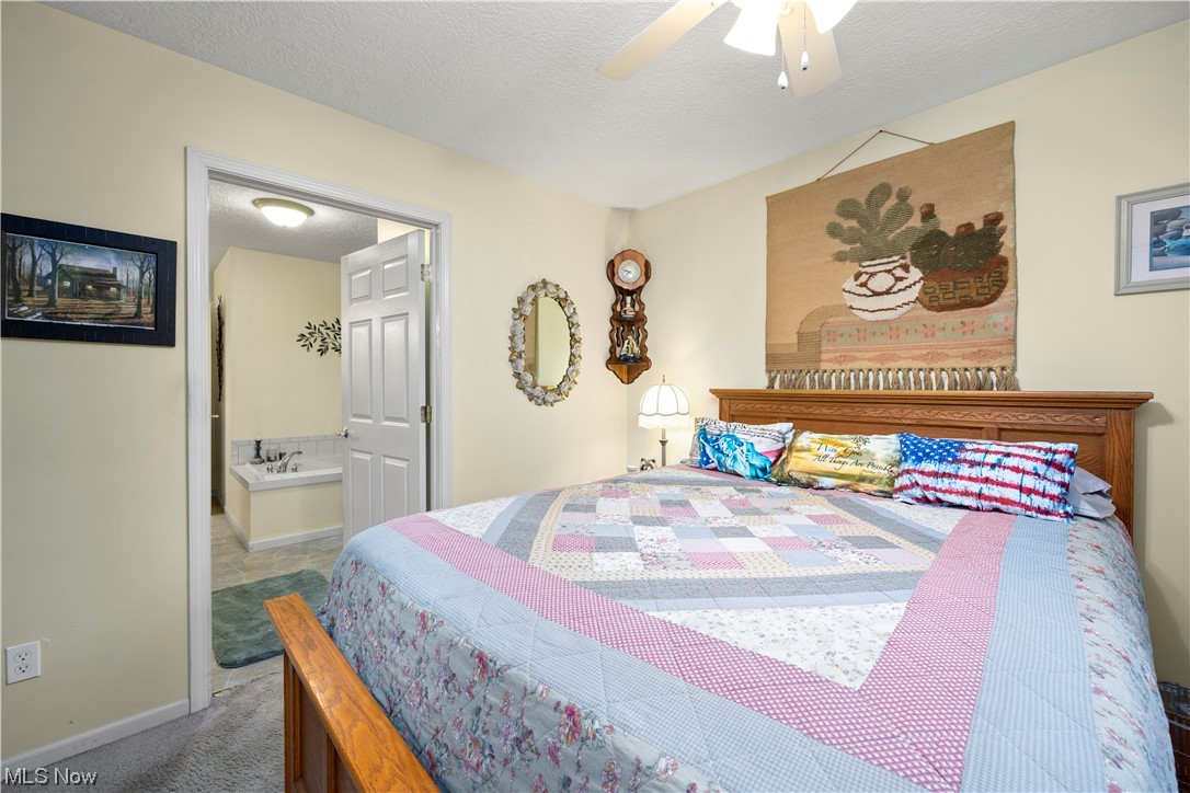 41038 Parsons Road Lagrange, OH 44050 - Photo 19 of 32 Bedroom featuring a textured ceiling, dark colored carpet, ensuite bath, and ceiling fan