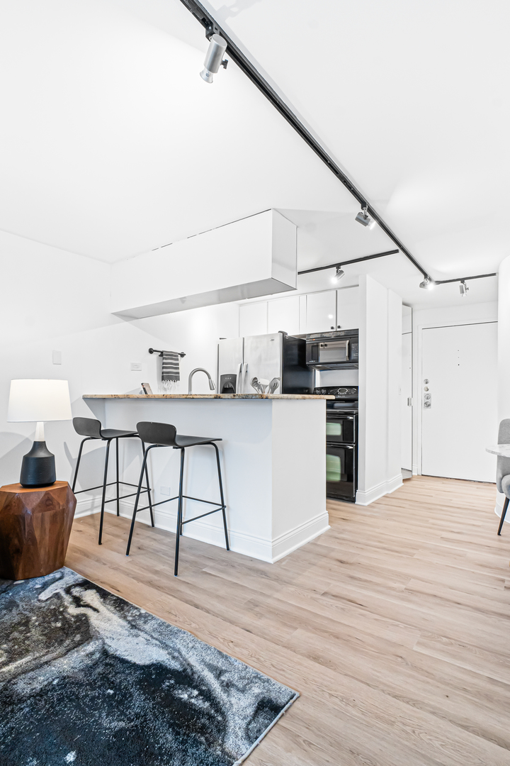 1221 North Dearborn Street, Unit PH8S Chicago, IL 60610 - Photo 7 of 24 a living room with stainless steel appliances kitchen island granite countertop furniture and a wooden floor
