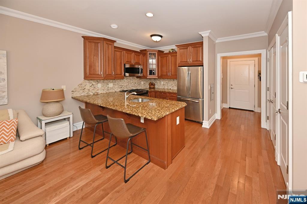 2303 Rio Vista Lane Northvale, NJ 07647 - Photo 7 of 30 a kitchen with stainless steel appliances granite countertop a stove a refrigerator a sink a dining table and chairs with wooden floor