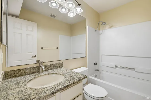 a bathroom with a granite countertop sink toilet a mirror and shower