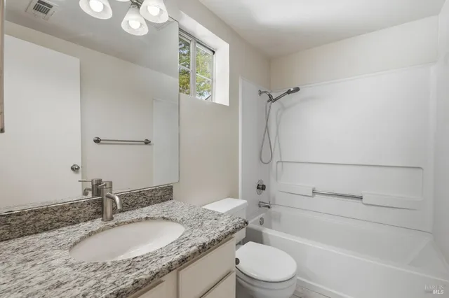 a bathroom with a granite countertop sink toilet and shower