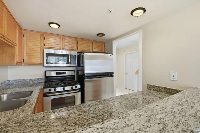 a kitchen with granite countertop a stove refrigerator and microwave