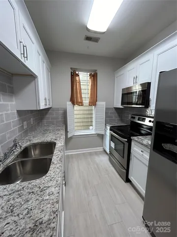 a kitchen with granite countertop a sink and steel appliances