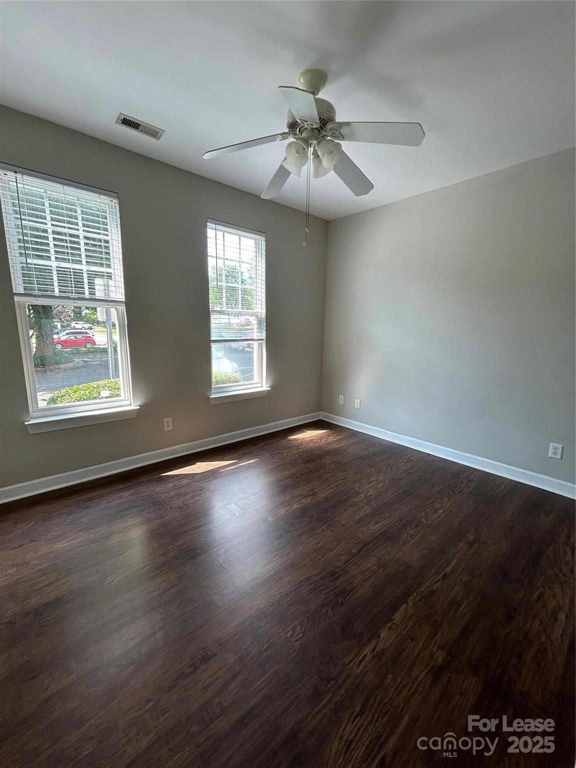 18605 Ruffner Drive, Unit 1D Cornelius, NC 28031 - Photo 9 of 14 an empty room with wooden floor chandelier fan and windows