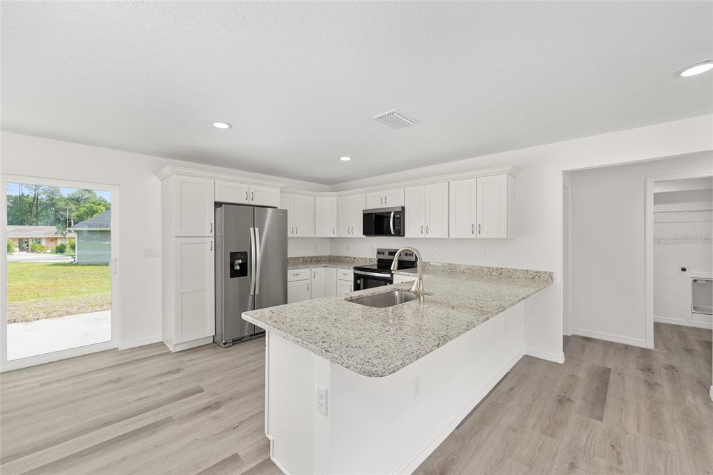 13019 Northeast 7th Loop Silver Springs, FL 34488 - Photo 18 of 35 a kitchen with stainless steel appliances granite countertop a sink dishwasher and a refrigerator with wooden floor