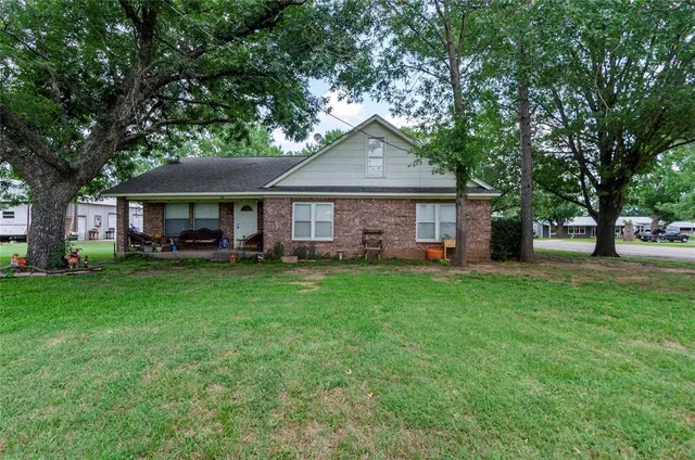 a front view of a house with a garden and trees
