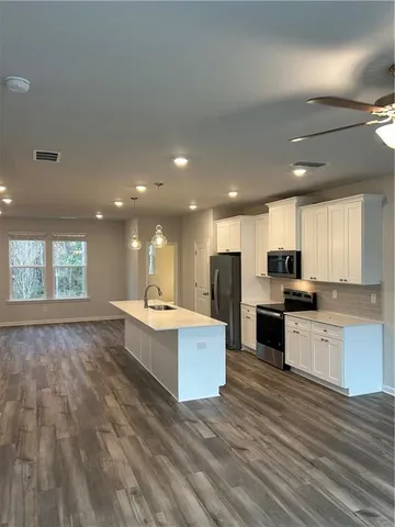 a large white kitchen with kitchen island a sink wooden floor and a stove top oven