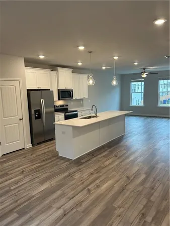 a large kitchen with stainless steel appliances granite countertop a large counter top a sink and a refrigerator