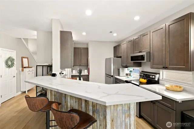a kitchen with stainless steel appliances a table chairs sink refrigerator and microwave
