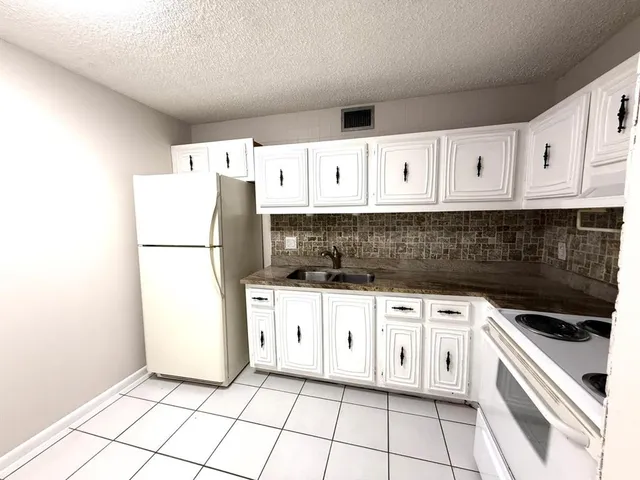 a kitchen with granite countertop white cabinets and refrigerator