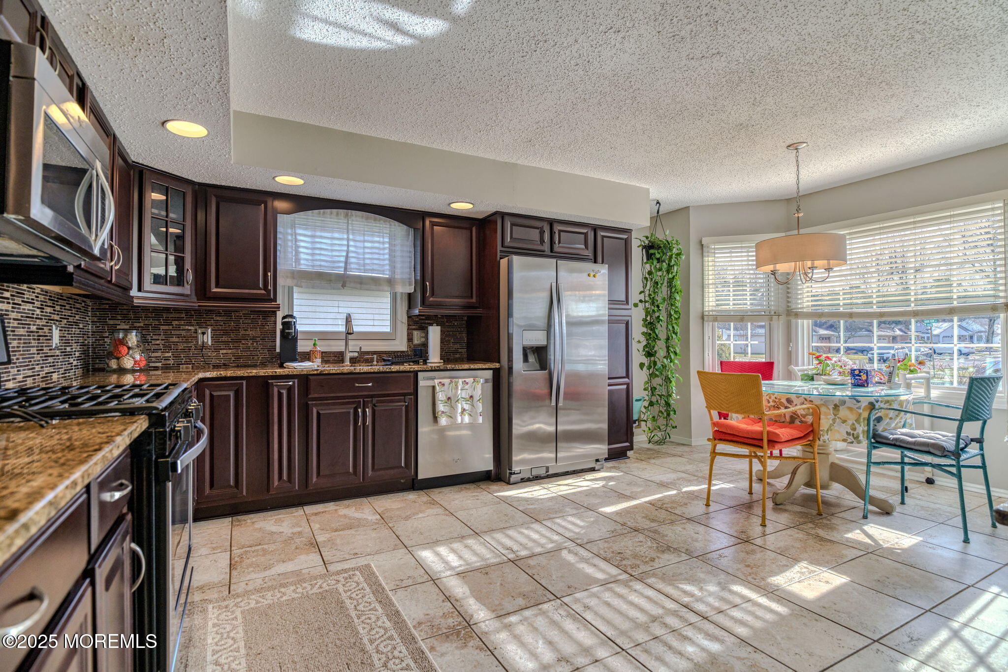 16 Deer Run Lane Brick, NJ 08724 - Photo 6 of 41 a kitchen with stainless steel appliances granite countertop a stove top oven a sink dishwasher a dining table and chairs with wooden floor
