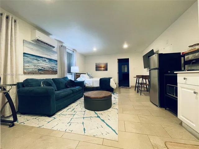 a living room with furniture and a refrigerator