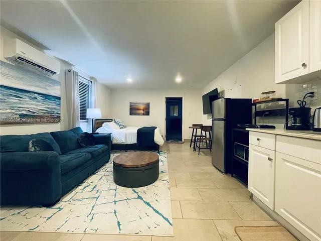 a living room with furniture a kitchen view and a refrigerator