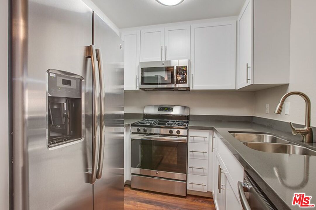 a kitchen with stainless steel appliances granite countertop a stove a refrigerator and a sink