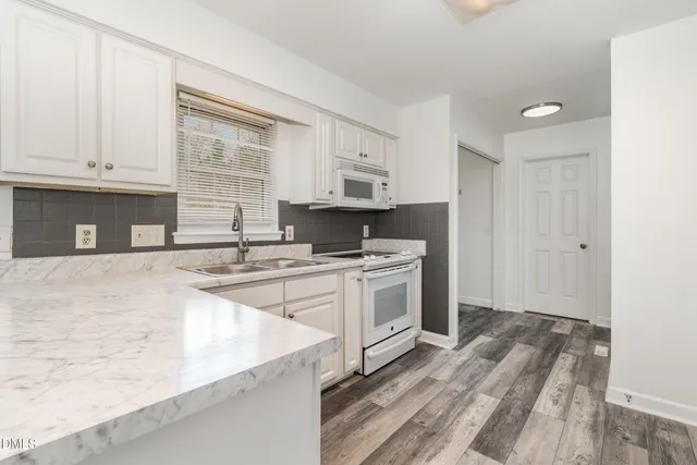 a kitchen with granite countertop a stove a sink and a microwave