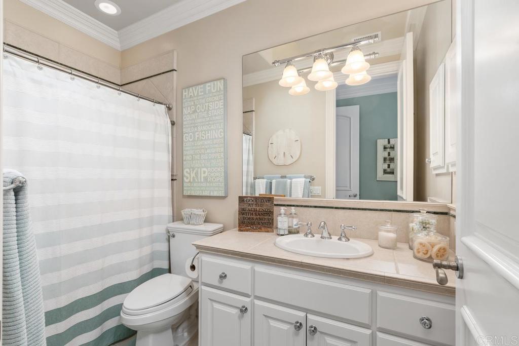 3056 Wildflower Drive Encinitas, CA 92024 - Photo 41 of 56 a bathroom with a granite countertop sink toilet a mirror a vanity and shower