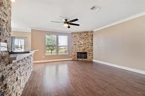 an empty room with wooden floor fan and windows
