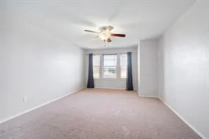 an empty room with chandelier fan and windows