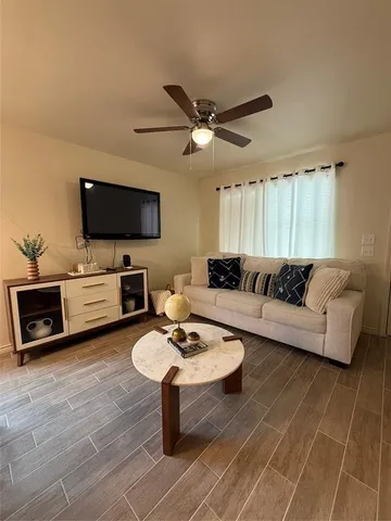 a living room with furniture a flat screen tv and kitchen view