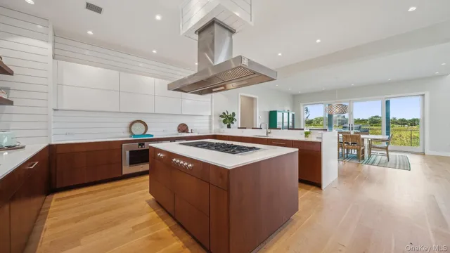 a kitchen with kitchen island a stove a wooden floor and a large window